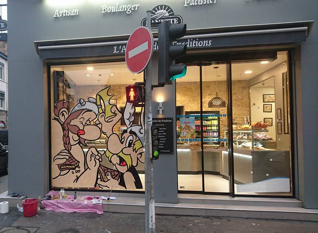 Vitrine de boulangerie pour la galette des rois : Astérix et Obélix dévorant une galette, peints en cours de réalisation