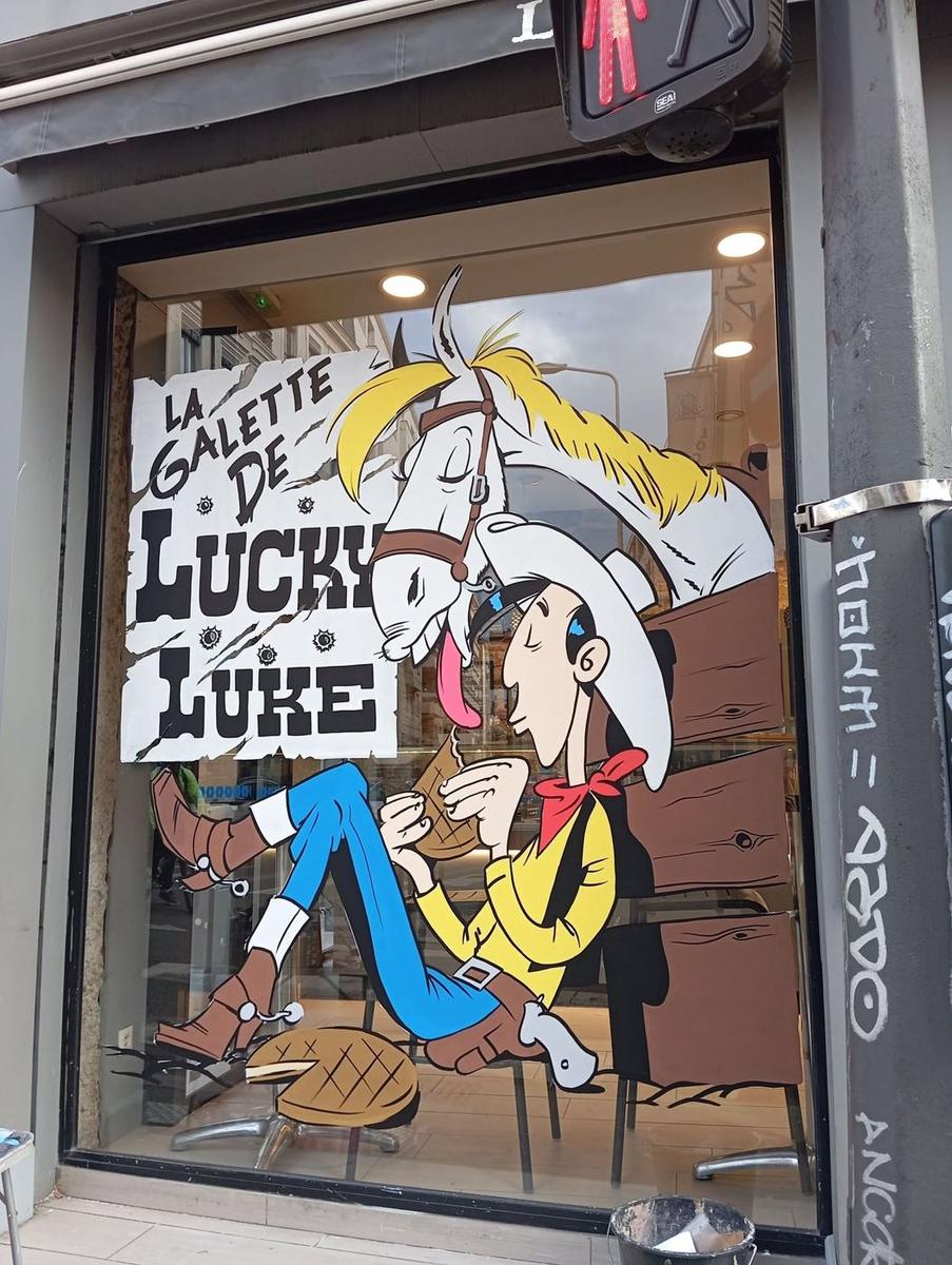 Lucky Luke dégustant une galette des rois, Jolly Jumper penché sur son épaule, sous le titre « La galette de Lucky Luke »
