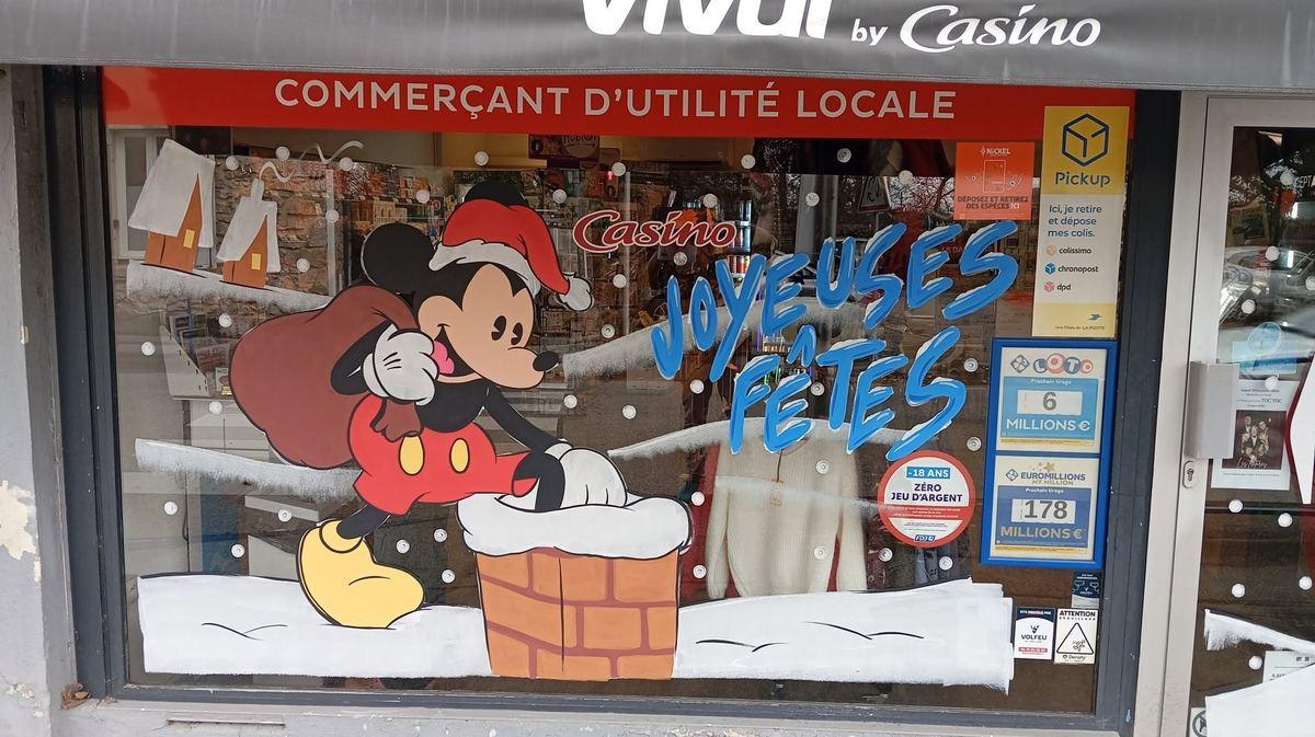 Vitrine Vival décorée pour Noël : Mickey en Père Noël sur une cheminée enneigée, lettrage « Joyeuses fêtes »