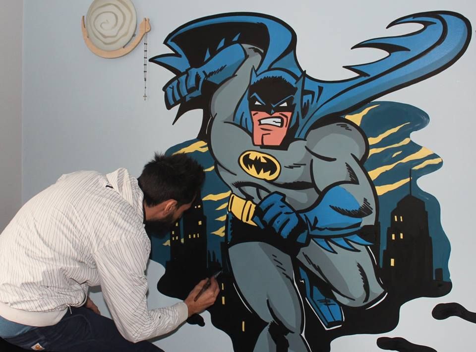 Raphaël peaufinant une fresque de Batman devant la ville de Gotham la nuit