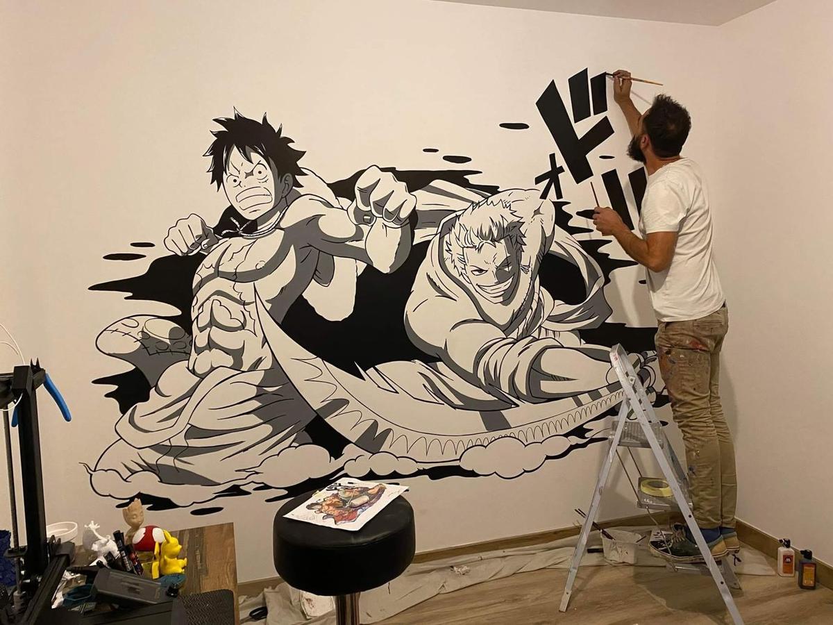 Raphaël peignant une grande fresque en noir et gris de Luffy et Zoro, avec une onomatopée manga