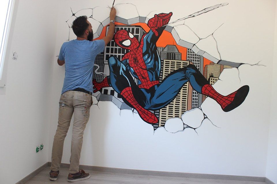 Raphaël peignant Spider-Man jaillissant d'un mur brisé sur fond de gratte-ciel, dans une chambre d'enfant