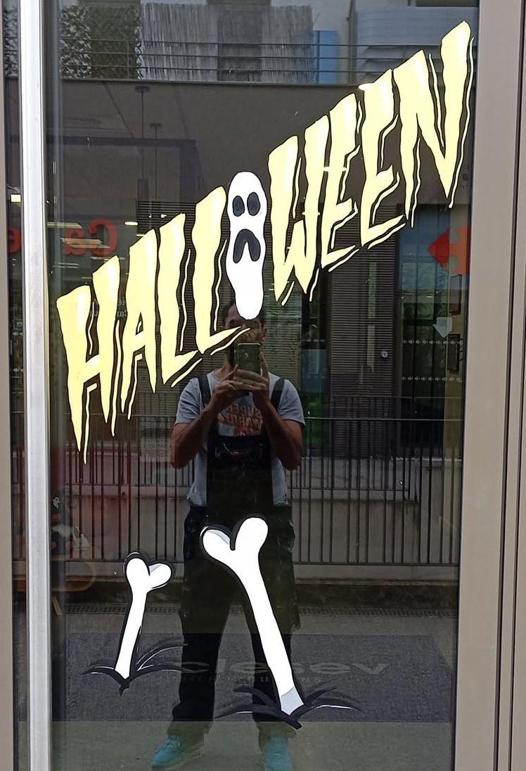 Porte d'entrée avec le lettrage « Halloween » peint à la main, un fantôme dans le O et des os
