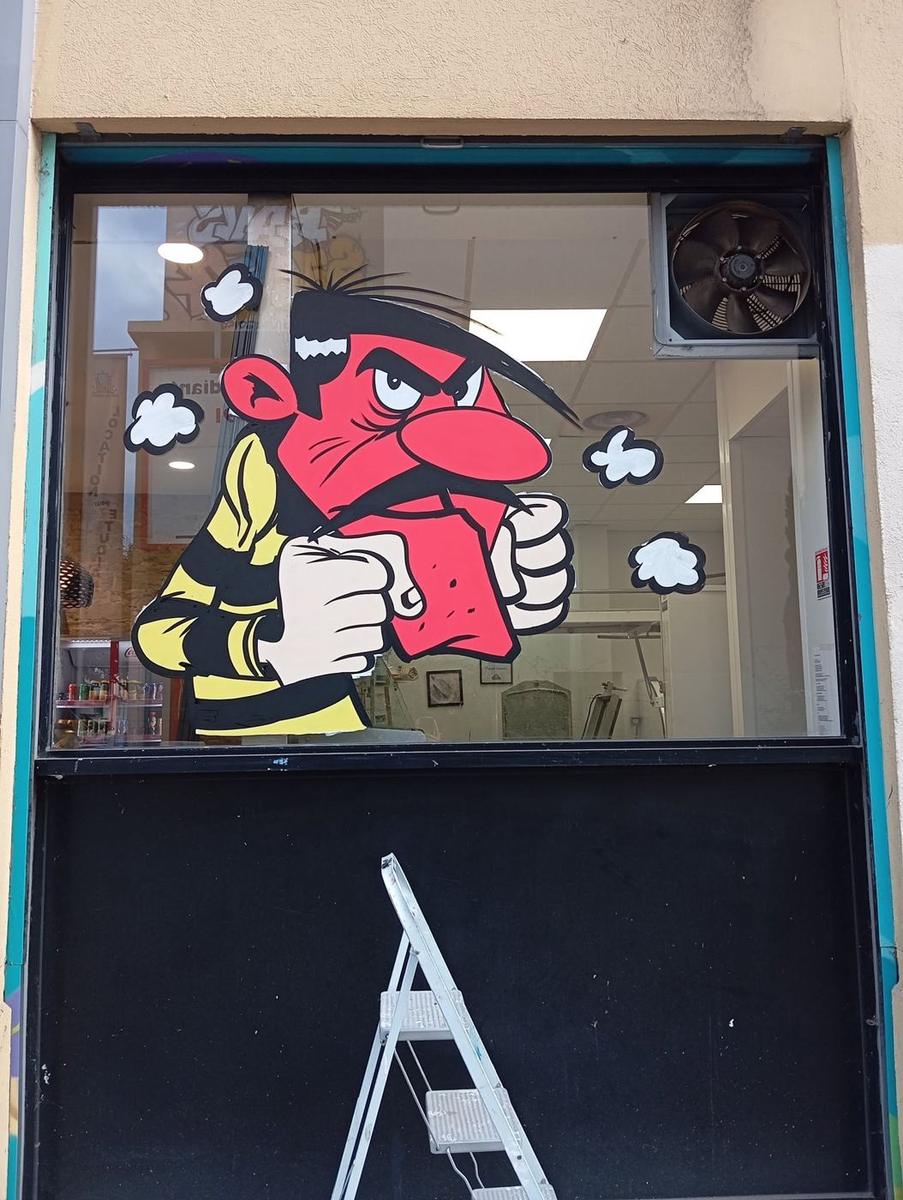 Joe Dalton furieux, une part de galette à la main, peint sur la vitrine voisine
