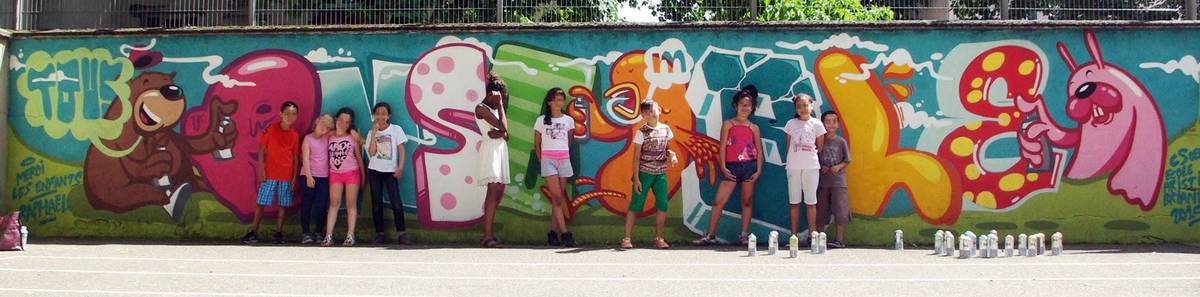 Les enfants de l'école primaire posant devant la fresque participative qu'ils ont peinte, visages floutés