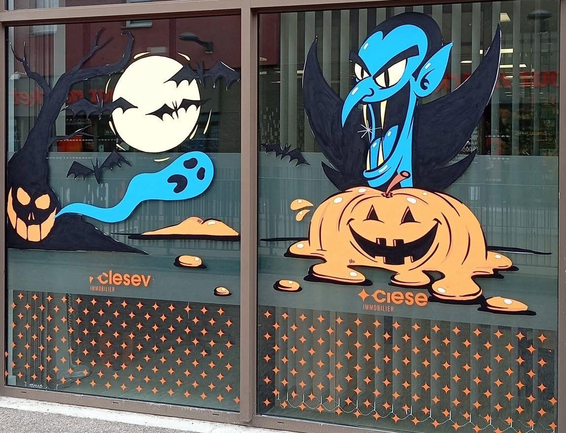 Deux vitrines d'Halloween : arbre-citrouille, pleine lune, chauves-souris et fantôme bleu, à côté du vampire