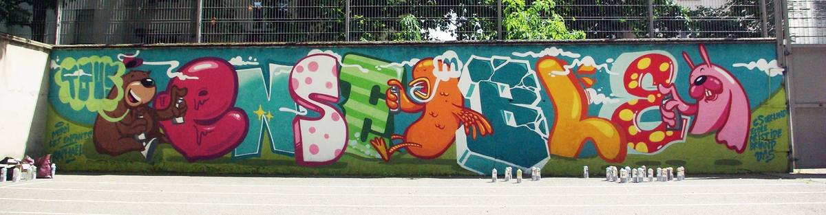 Fresque participative réalisée avec les enfants d'une école primaire : grandes lettres colorées en style graffiti et personnages animaux tenant des bombes de peinture