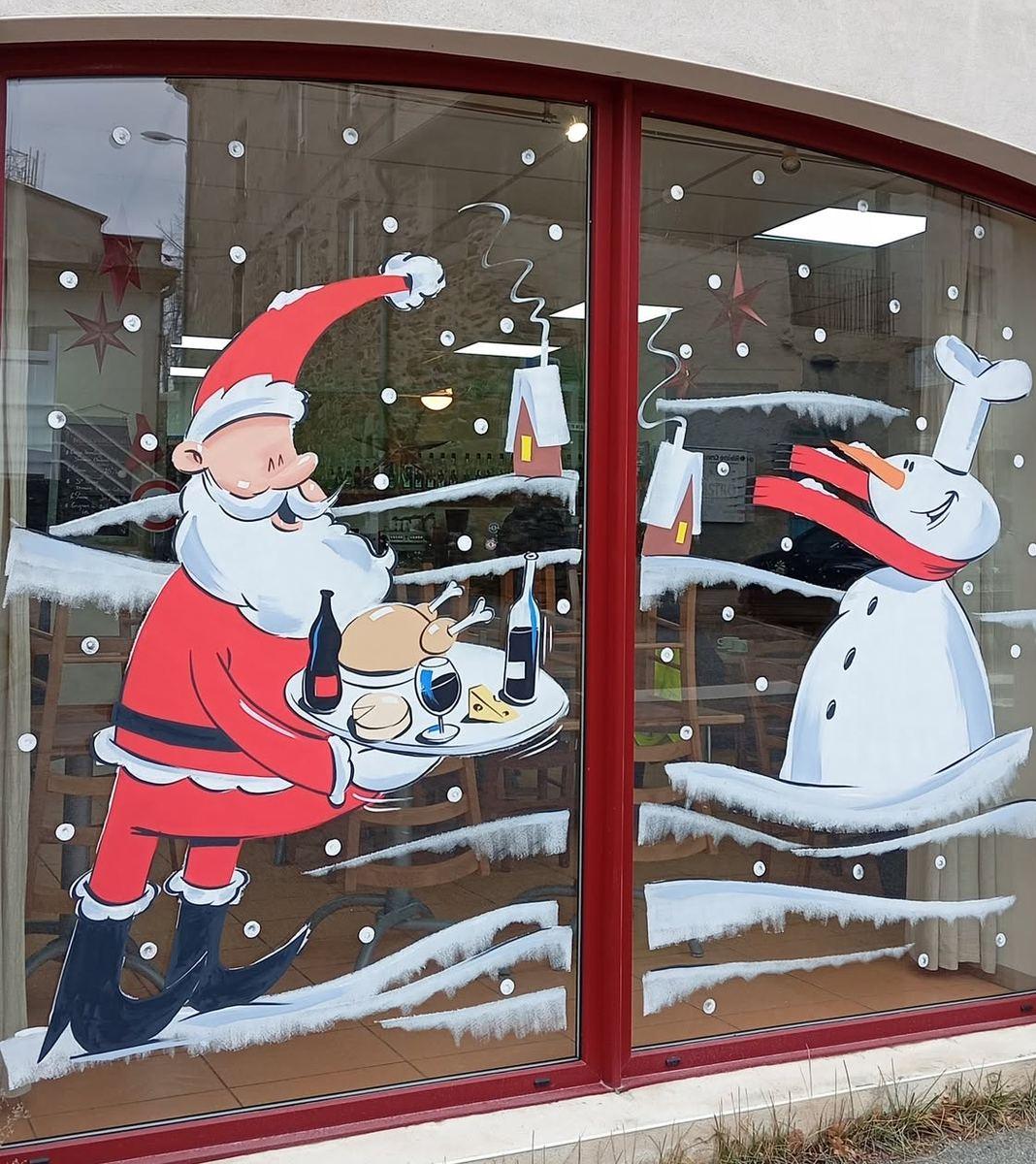 Vitrine de Noël : Père Noël portant un plateau avec volaille, vin et fromages, bonhomme de neige en toque de cuisinier