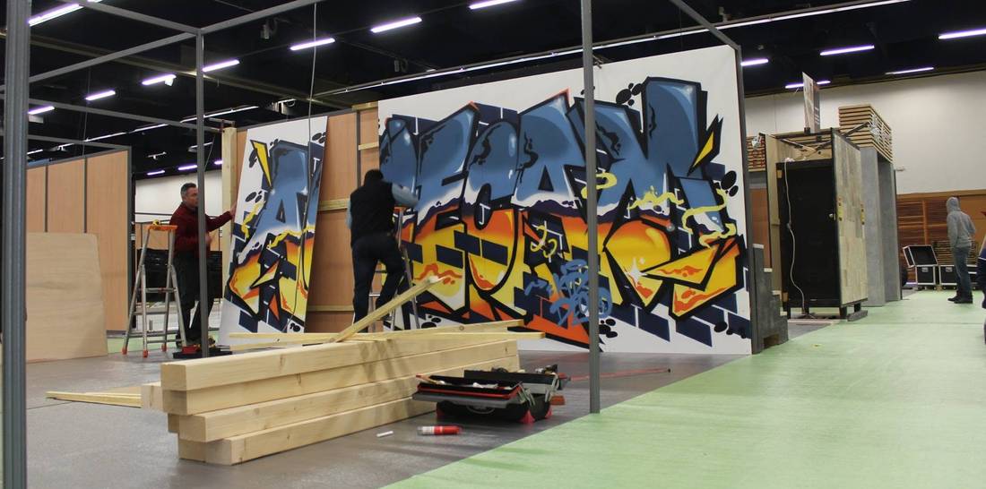 Montage du graffiti sur le stand du salon d'exposition par l'équipe de la menuiserie