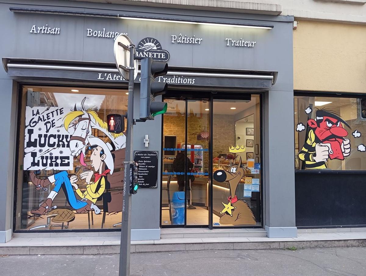 Vue d'ensemble de la devanture : Lucky Luke et Jolly Jumper, Rantanplan et Joe Dalton peints sur les vitrines de la boulangerie