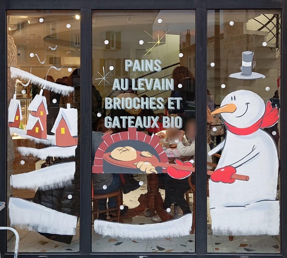 Bonhomme de neige enfournant une miche dans un four à pain, lettrage « Pains au levain, brioches et gâteaux bio »