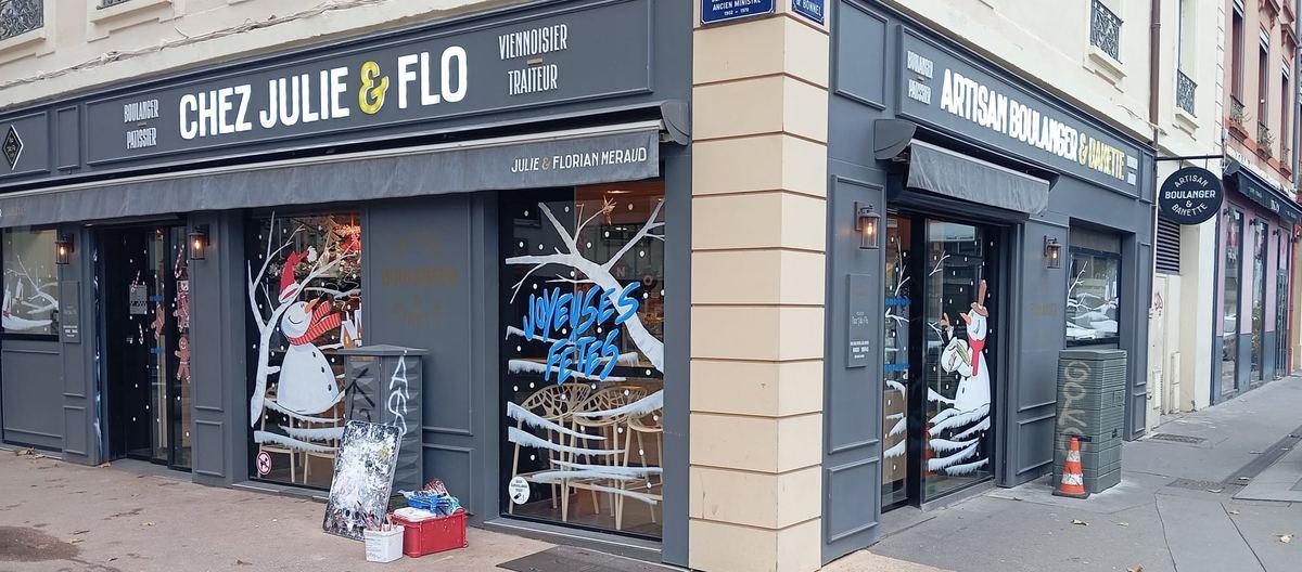 Façade de la boulangerie Chez Julie & Flo décorée pour Noël : bonshommes de neige, arbres enneigés et lettrage « Joyeuses fêtes »
