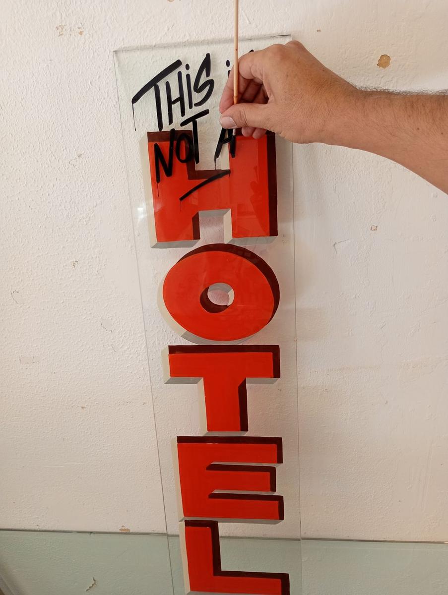 Raphaël peignant les finitions du panneau « Hotel » au pinceau