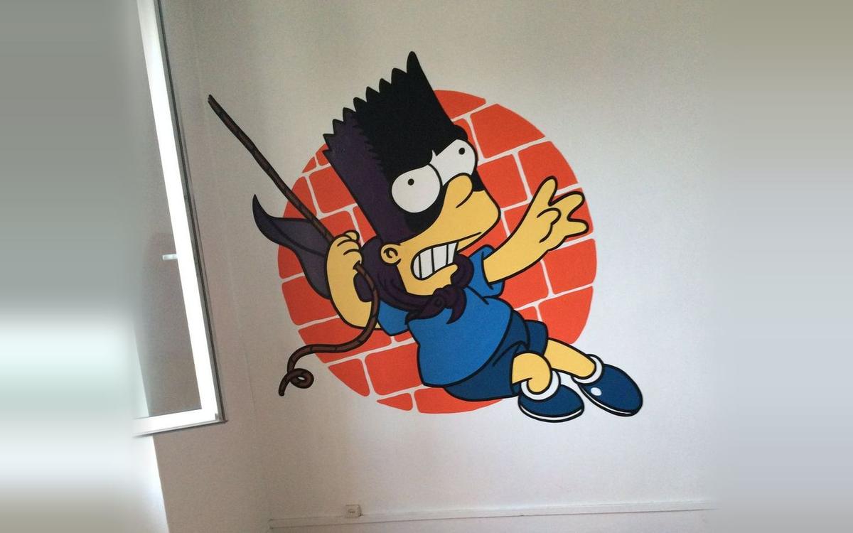 Bart Simpson en Bartman, suspendu à une corde devant un mur de briques orange, peint dans une chambre