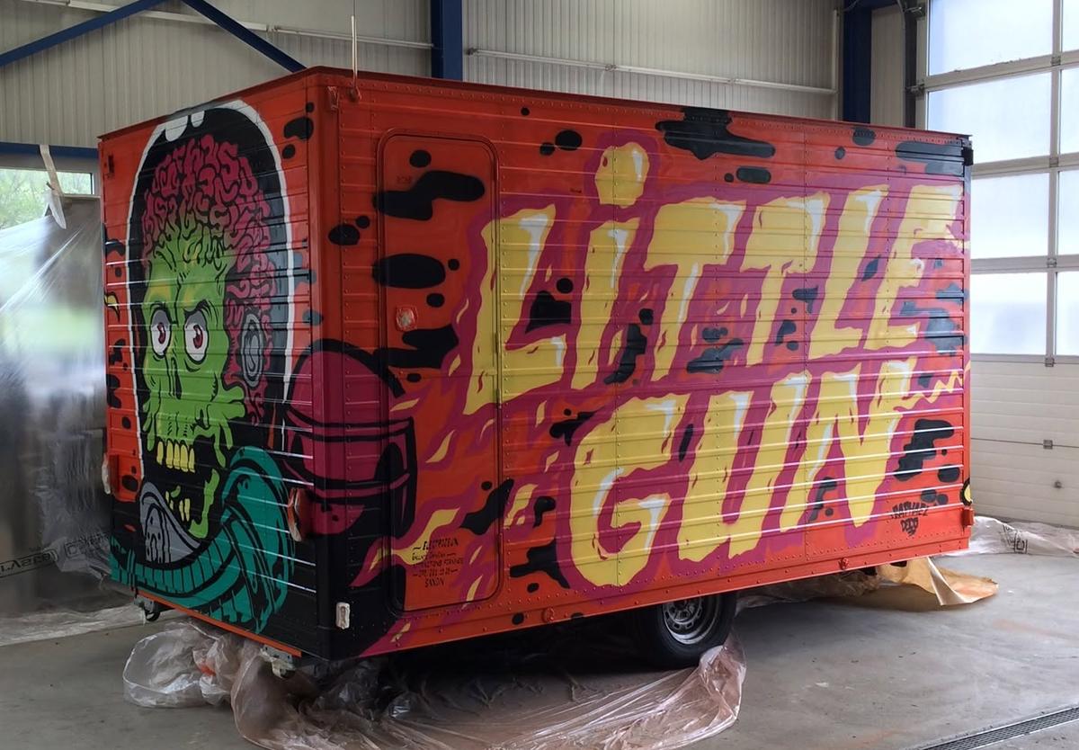 Caravane de fête foraine « Little Gun » : grand lettrage jaune et martien au cerveau apparent, peints à la main